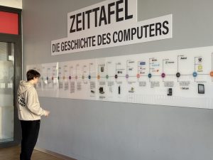 Schüler steht vor der Zeittafel der Geschichte der Informatik